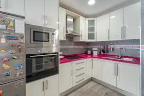 A modern kitchen with stainless steel appliances, white cabinets, and a pink countertop. - Vacation Apartment 'Apto Jardin Del Sol Beach' with Shared Pool, Wi-Fi and Air Conditioning (Santiago del Teide)