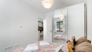 Ein Schlafzimmer mit einem Bett, einem großen Spiegel und einer Deckenleuchte.