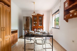 Un coin repas comprenant une table noire, des chaises transparentes, un meuble en bois et un réfrigérateur.