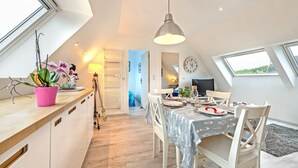 A dining area with a table set for two, a ceiling light, and a view through a skylight.