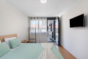 Habitación de hotel moderna con cama, televisor, vestidor y vista a la ciudad.