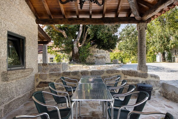 Un edificio de piedra con un área de estar al aire libre y techada, que incluye una mesa y sillas.