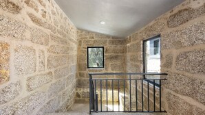 A stone-walled room with a small window and a black railing. - Room 4 with private bathroom, Wi-Fi and air conditioning (Rossas)