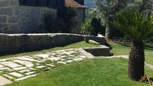A courtyard with a stone wall, a palm tree, and a building with a tiled roof. - Room 4 with private bathroom, Wi-Fi and air conditioning (Rossas)