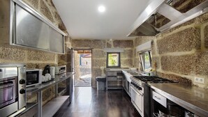 A kitchen with granite countertops, stainless steel appliances, and a stone wall. - Room 4 with private bathroom, Wi-Fi and air conditioning (Rossas)