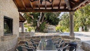 A stone building with a covered outdoor seating area, including a table and chairs.