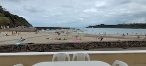 A beach with people, boats, and a stone wall.