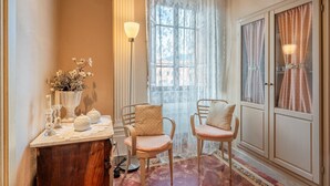 Habitació amb un tocador de fusta, dues cadires, una finestra gran amb cortines i un armari.