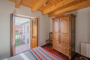 A bedroom with a bed, wooden wardrobe, and a sliding glass door to a balcony.