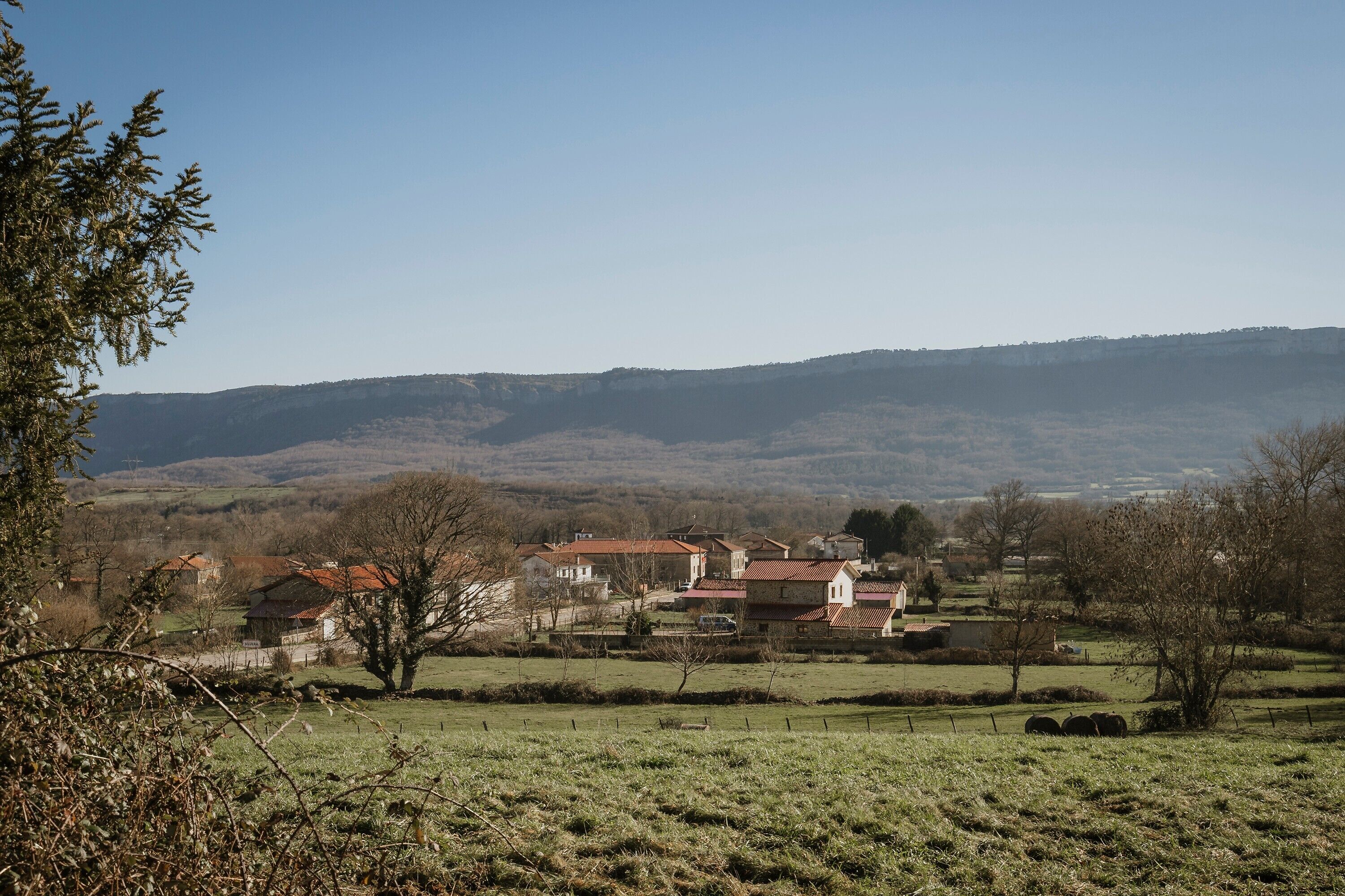 A rural landscape with houses, open fields, and distant hills.