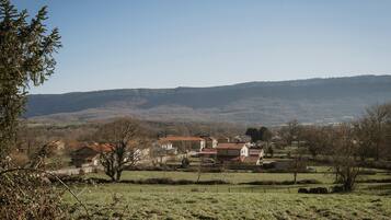 A rural landscape with houses, open fields, and distant hills.