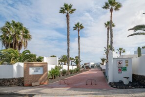 A pathway leading to Shangrila Park with palm trees and a white building. - Vacation Apartment 'Loft Valentina 2' with Shared Pool, Shared Terrace and Wi-Fi (Montaña Roja)
