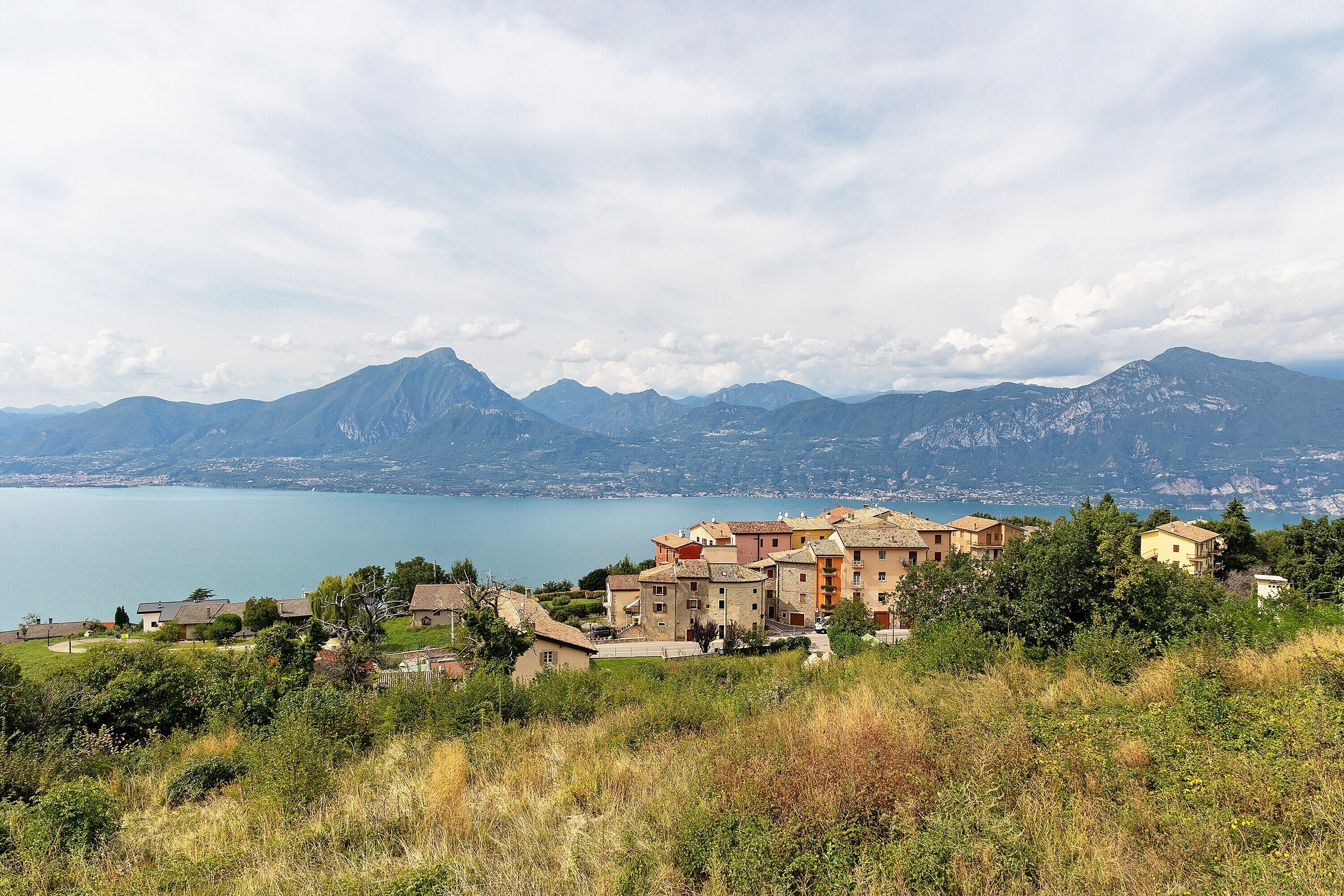 A coastal village with buildings overlooking a lake and mountains.