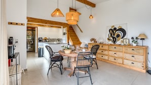 A dining area with a wooden table, chairs, and a staircase leading to a kitchen. - Le Mas De Coeur with Mountain View, Wi-Fi and Air Conditioning (Bédarieux)