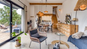 A modern interior with a dining area, a sofa, a staircase, and a large window. - Le Mas De Coeur with Mountain View, Wi-Fi and Air Conditioning (Bédarieux)