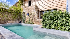 A swimming pool with stone walls, surrounded by greenery and a wooden building. - Le Mas De Coeur with Mountain View, Wi-Fi and Air Conditioning (Bédarieux)