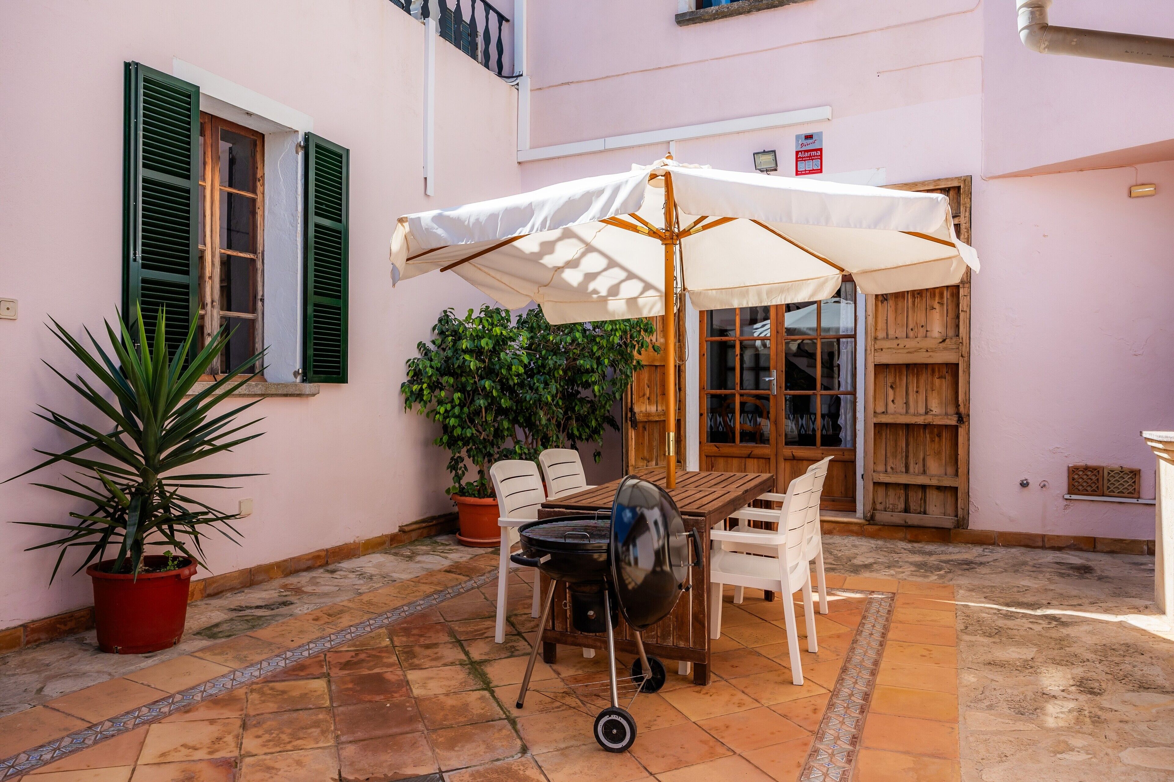 A patio with a table, chairs, a grill, and an umbrella.