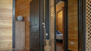 Un intérieur en bois avec une porte, un vase en osier et un banc.
