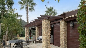 Un espace patio agrémenté de piliers en pierre, d’une pergola, de sièges d’extérieur et offrant une vue sur le paysage environnant.