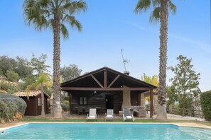 A wooden cabin with a pool, surrounded by palm trees and a clear sky. - Country House 'Villa Ronda' with Mountain View, Wi-Fi and Air Conditioning (Ronda)