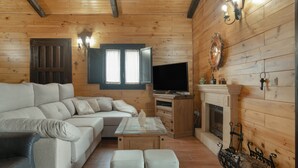 Un intérieur en bois avec un canapé, une télévision, une cheminée et des murs en bois.