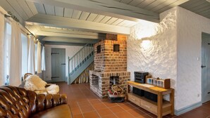 Un salon avec une cheminée en briques, un canapé en cuir et un escalier.