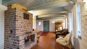 Une pièce avec une cheminée en briques, des meubles en bois et une vue sur l’extérieur.