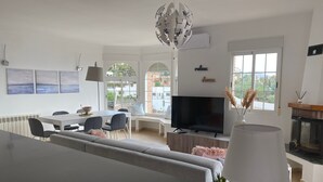Una sala de estar moderna con sofá, mesa de comedor, televisor y chimenea.