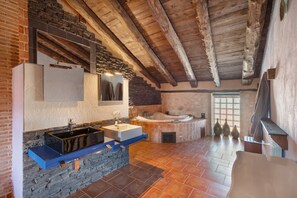 Une salle de bain rustique avec un lavabo en pierre, une baignoire et un grand miroir.