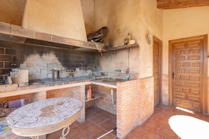 An outdoor kitchen with a brick counter, a sink, and a hanging shelf.
