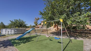 Un parque infantil con tobogán, columpios y una estructura para escalar.