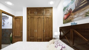 Un dormitorio con una cama grande, un armario de madera y un cuadro de un barco en la pared.