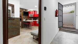 Una cocina moderna con armarios rojos, un comedor con dos sillas y un pequeño banco.