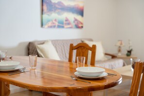 A dining table with plates, cutlery, and glasses, a wooden chair, and a painting on the wall.