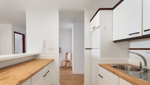 A kitchen with white cabinets, a wooden countertop, and a stainless steel sink. - Tomasol Vacation Apartment with Sea Views, Private Terrace, and Wi-Fi (Los Cristianos)
