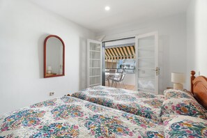 A bedroom with a bed, a mirror, and an open door leading to a balcony.