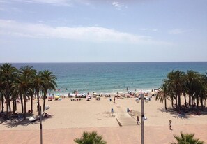 Una playa con palmeras, sombrillas y gente.