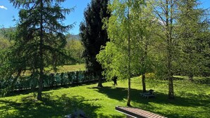 A well-maintained garden with a variety of trees, a small brick structure, and a clear blue sky. - Villa Giulia - Marguareis (Piemonte)