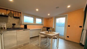 A compact kitchen with a dining area, a built-in oven, and a window overlooking a snowy landscape. - Villa Giulia - Marguareis (Piemonte)
