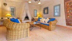 Una habitación acogedora con mobiliario de mimbre, chimenea y paredes decoradas.