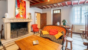 Ein Wohnzimmer mit Kamin, einer Couch mit Kissen, einem Holztisch und einem großen abstrakten Gemälde.