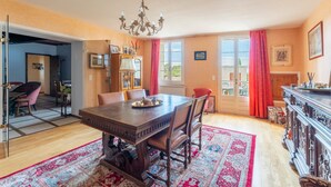 Ein Esszimmer mit einem Holztisch, Stühlen, einer Chandelier und einem großen Fenster mit Vorhängen.