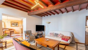 Ein Wohnzimmer mit Sofa, Sessel, Couchtisch aus Holz und Fernseher.