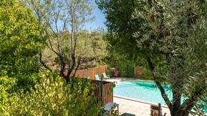Ein Garten mit Schwimmbecken, umgeben von Bäumen und einem Holzzaun.