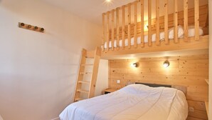Ein Stockbett mit einer Leiter, ein Nachttisch und ein an der Wand befestigtes Regal.