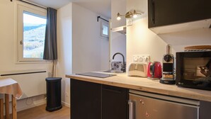 Eine kleine Küche mit Fenster, Spüle, Toaster, Wasserkocher und Mikrowelle.