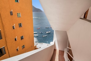 Une vue depuis un balcon donnant sur la mer, avec des bateaux, un immeuble doté de nombreuses fenêtres et un escalier.