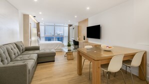 Ein modernes Hotelzimmer mit einem Bett, einer Couch, einem Esstisch und einem Fernseher.