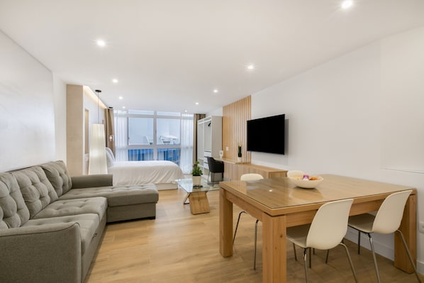 Une chambre d’hôtel moderne équipée d’un lit, d’un canapé, d’une table à manger et d’un téléviseur.