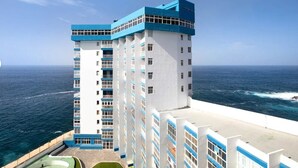 Ein Hochhaus-Hotel mit mehreren Etagen, einer auffälligen blau-weißen Farbgebung und Blick auf den Ozean.